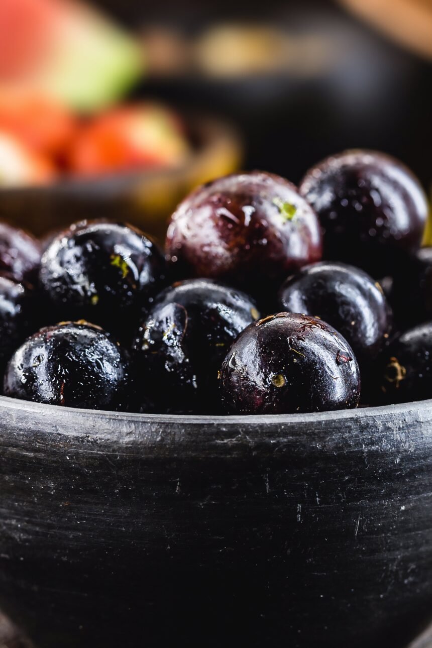 Jaboticaba or jabuticaba, Brazilian and South American fruit, in a clay pot. with tropical fruits in the background.